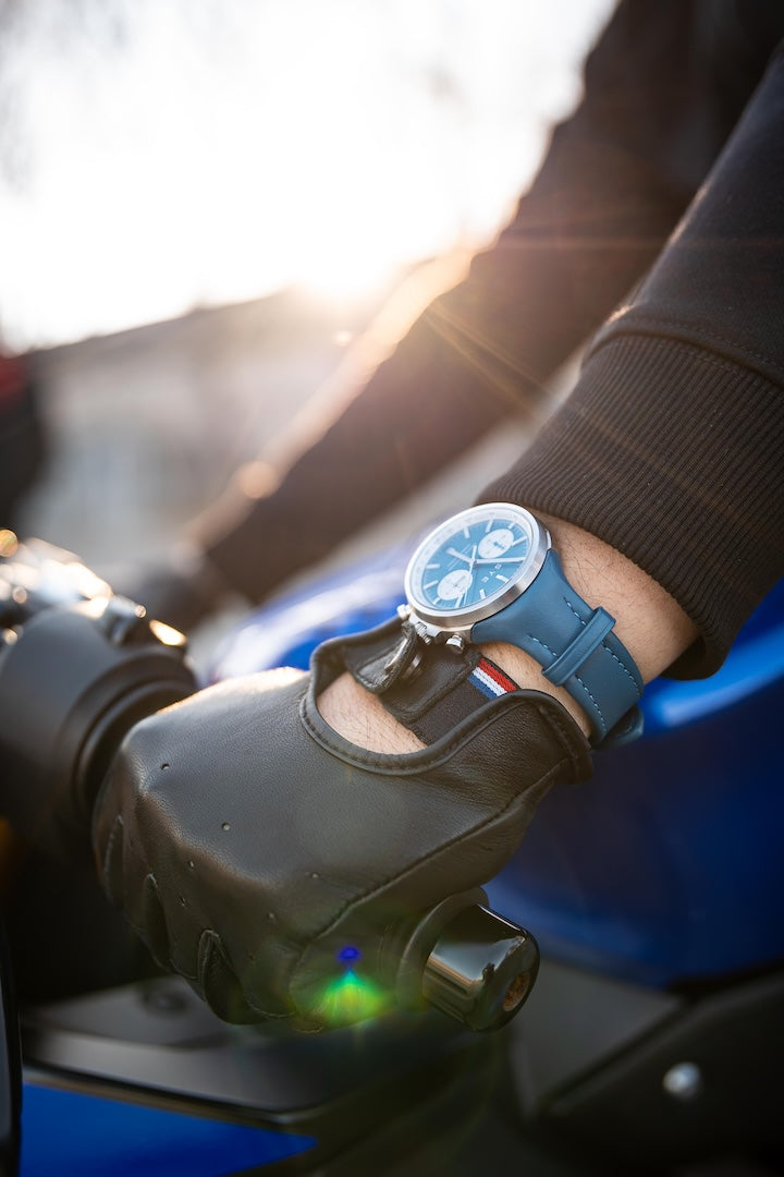 Person wearing a glove and watch on a motorcycle with a blurred background