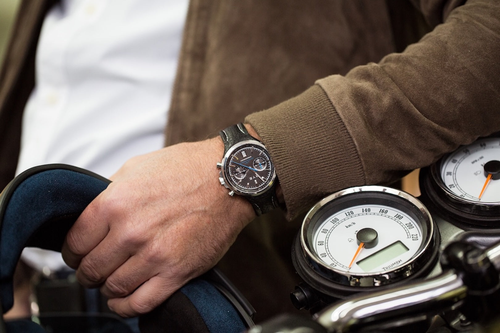 Person wearing a watch on a motorcycle with a close-up of the watch face.