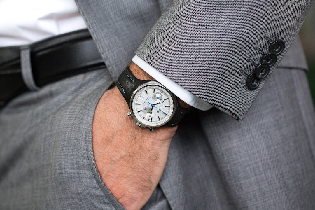Person wearing a gray suit with a watch on their wrist