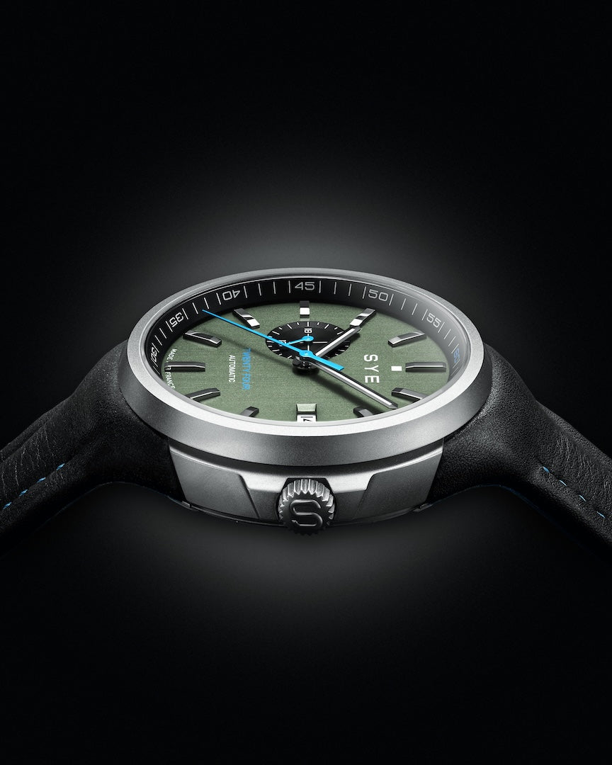 Watch with a green dial and black strap on a dark background