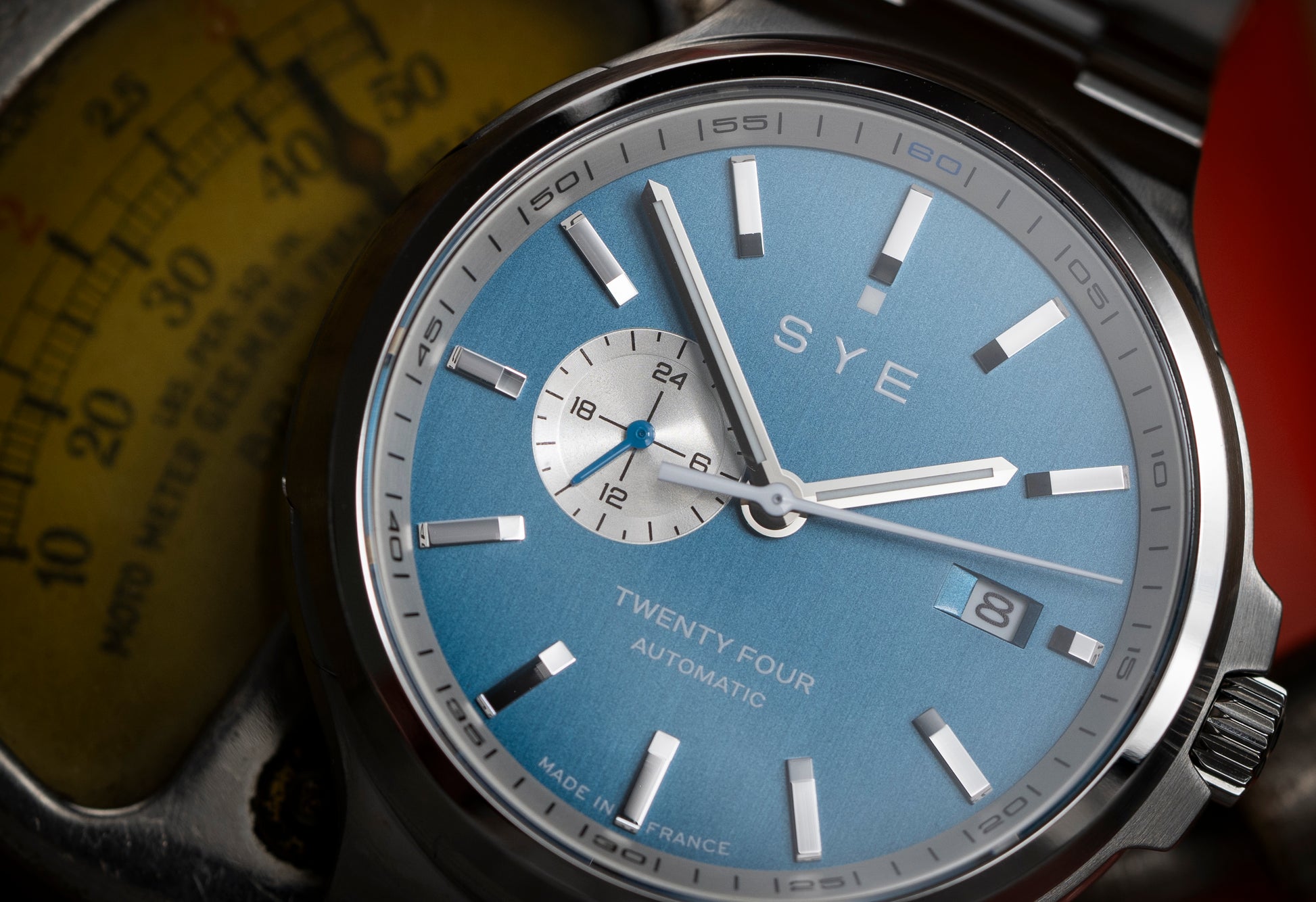 SYE watch with blue face and silver case on a blurred background