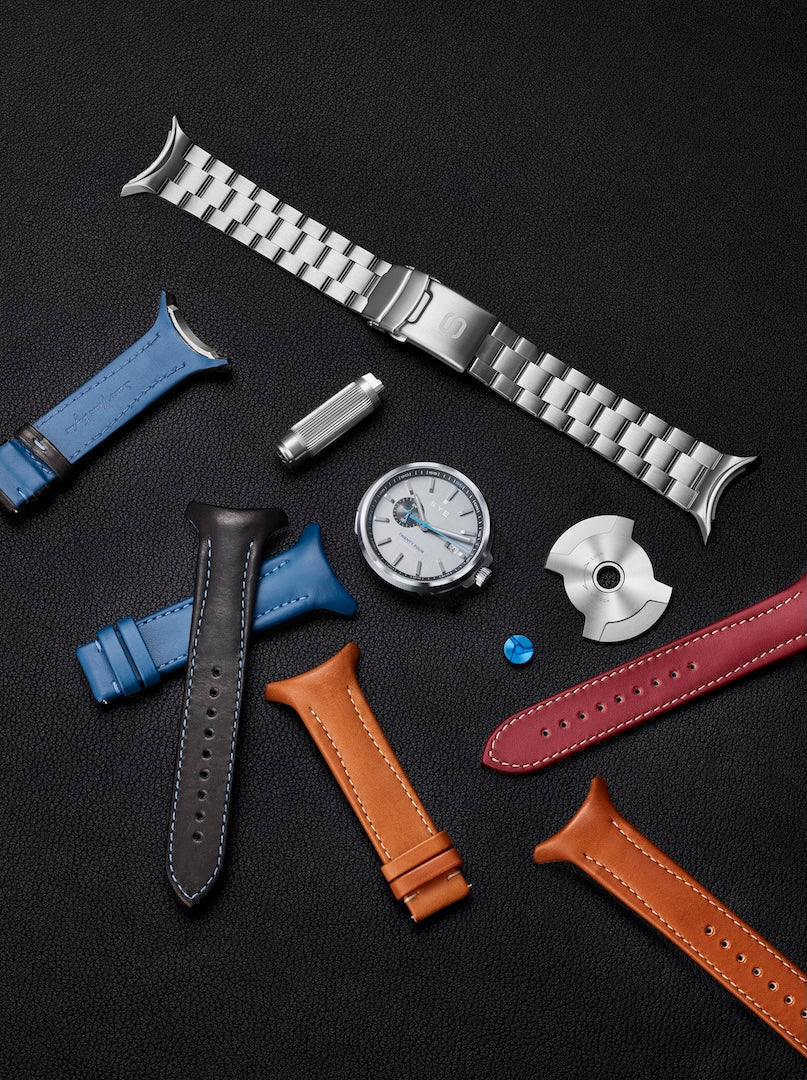 Collection of watch straps and watch parts on a dark surface