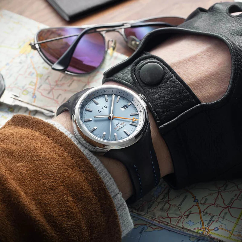 Person wearing a watch with a leather strap on a map background