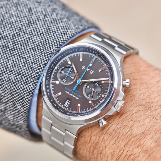 Close-up of a person wearing a silver watch with a detailed face.