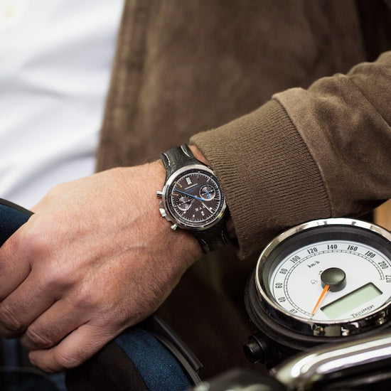 Person wearing a watch on a motorcycle with a close-up of the watch face.