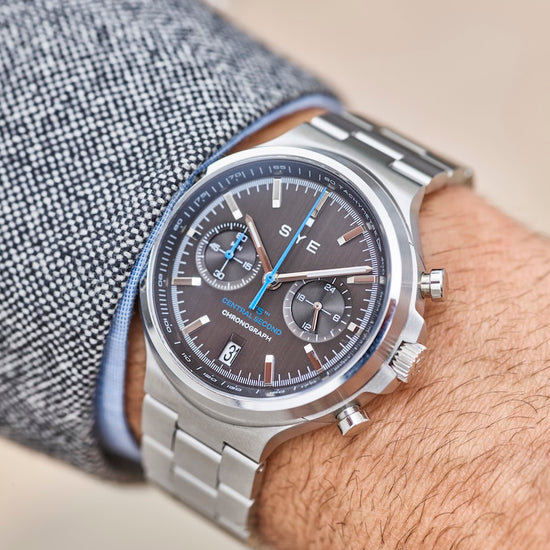 Close-up of a wrist wearing a silver watch with a detailed face.