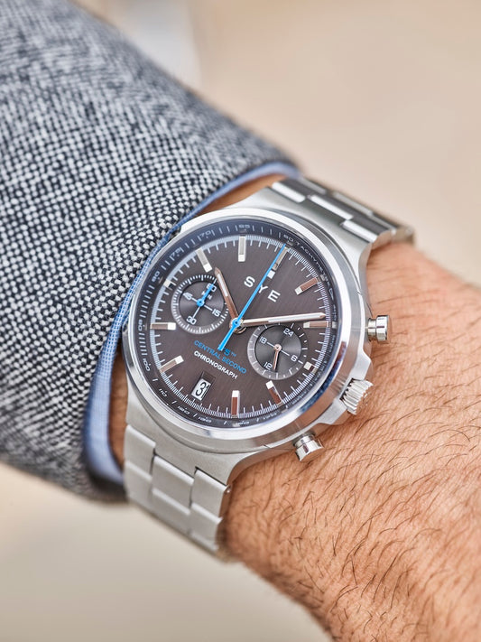 Close-up of a wrist wearing a silver watch with a detailed face.
