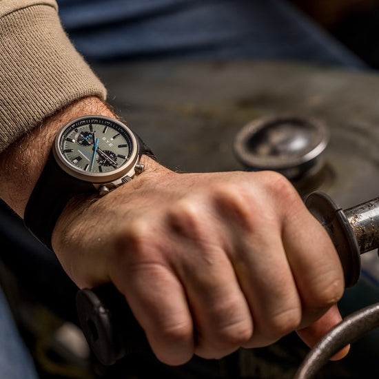 Hand wearing a watch on a vintage-style vehicle steering wheel