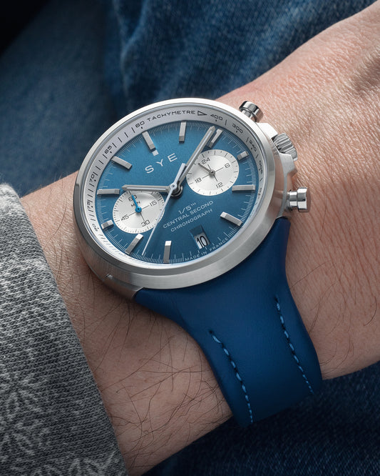Blue watch with silver case on a wrist against a denim background