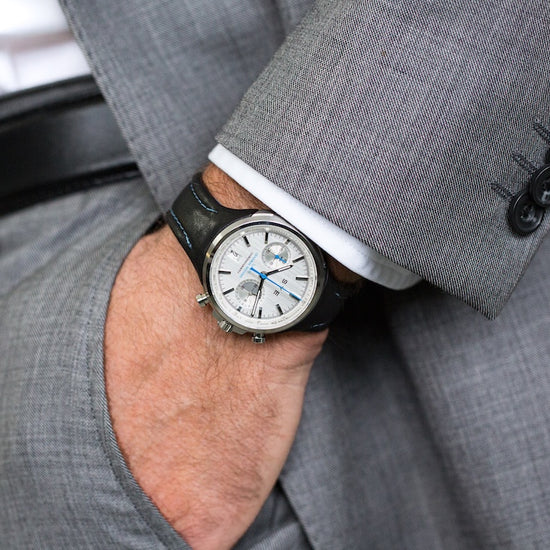 Person wearing a gray suit with a watch on their wrist