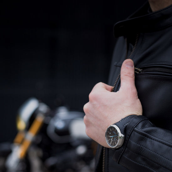 Person wearing a black jacket with a blurred motorcycle in the background
