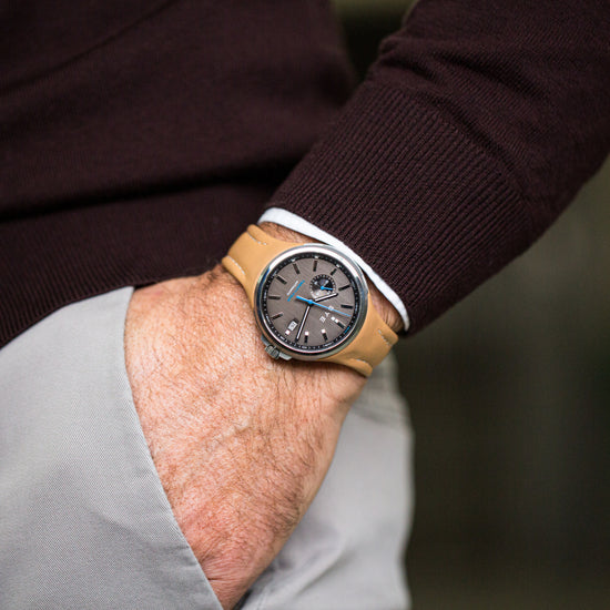 Person wearing a watch with a brown strap on a blurred background