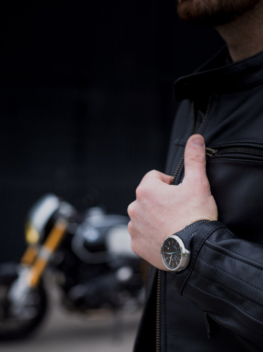 Person wearing a black jacket with a blurred motorcycle in the background