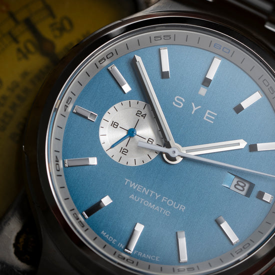 SYE watch with blue face and silver case on a blurred background