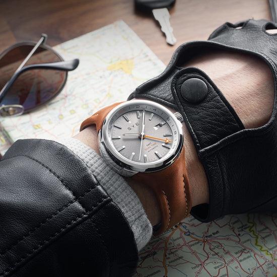 Hand wearing a leather glove with a watch on a map background