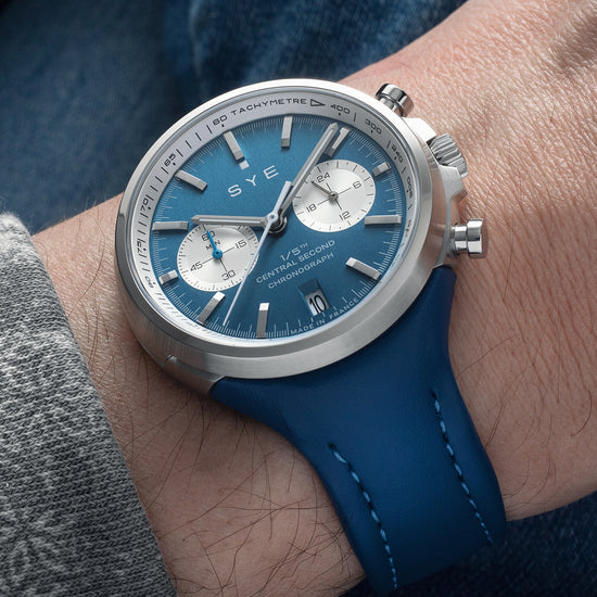 Blue watch with silver case on a wrist against a denim background
