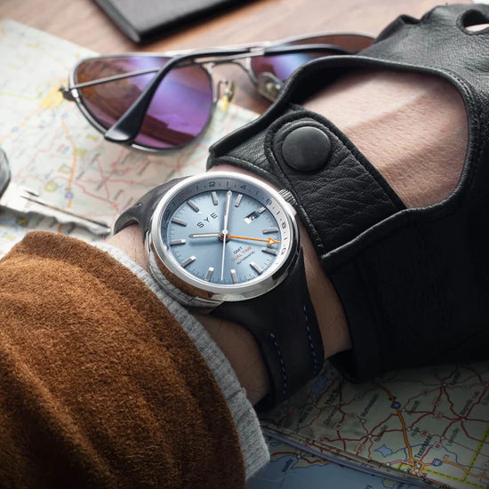 Person wearing a watch with a leather strap on a map background